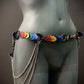Colorful heart-shaped belt with metal chains on gray mannequin, vibrant and edgy style, bold emotion