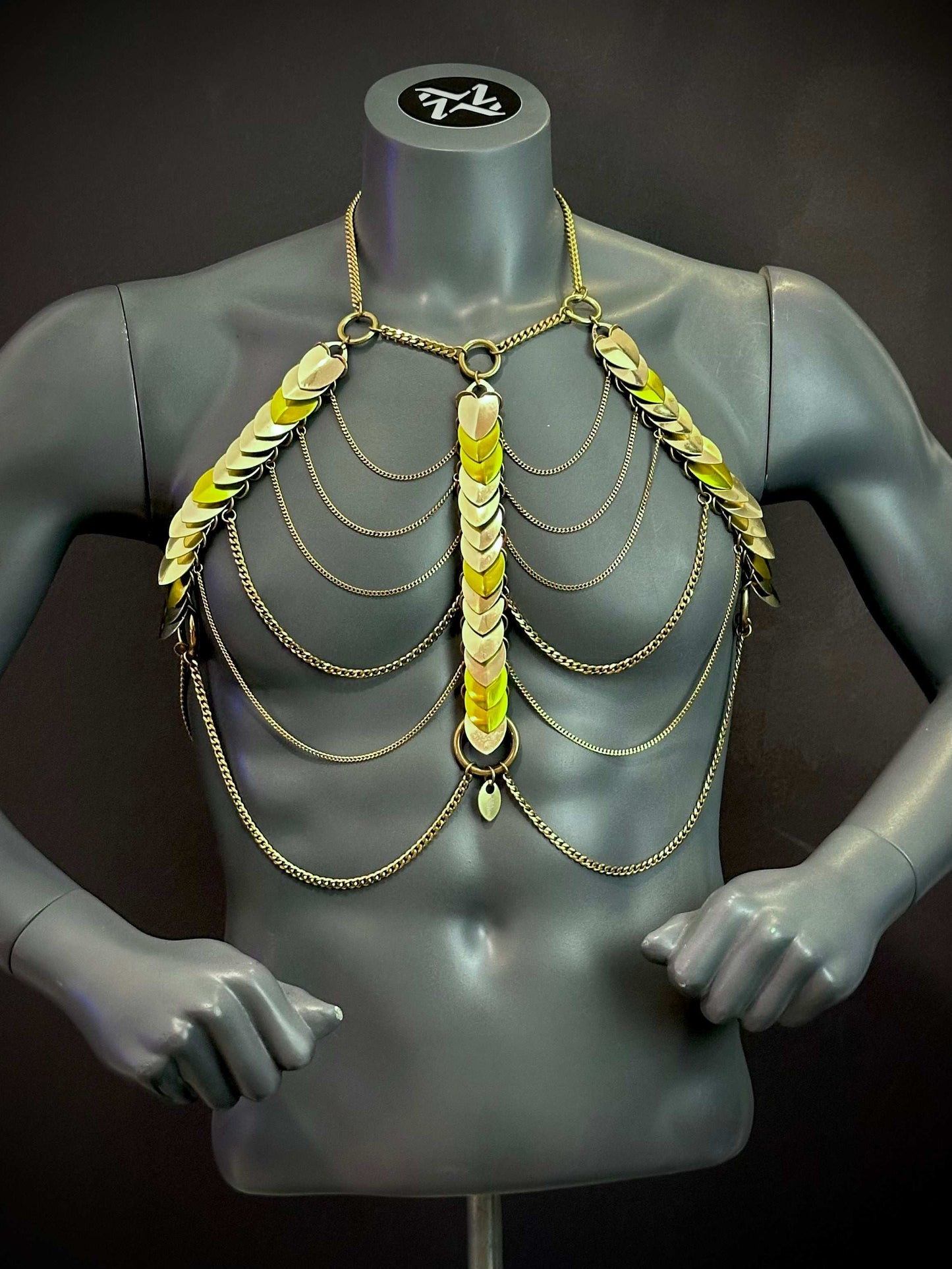 Gold chain body harness with metallic scales on gray mannequin, edgy and bold style