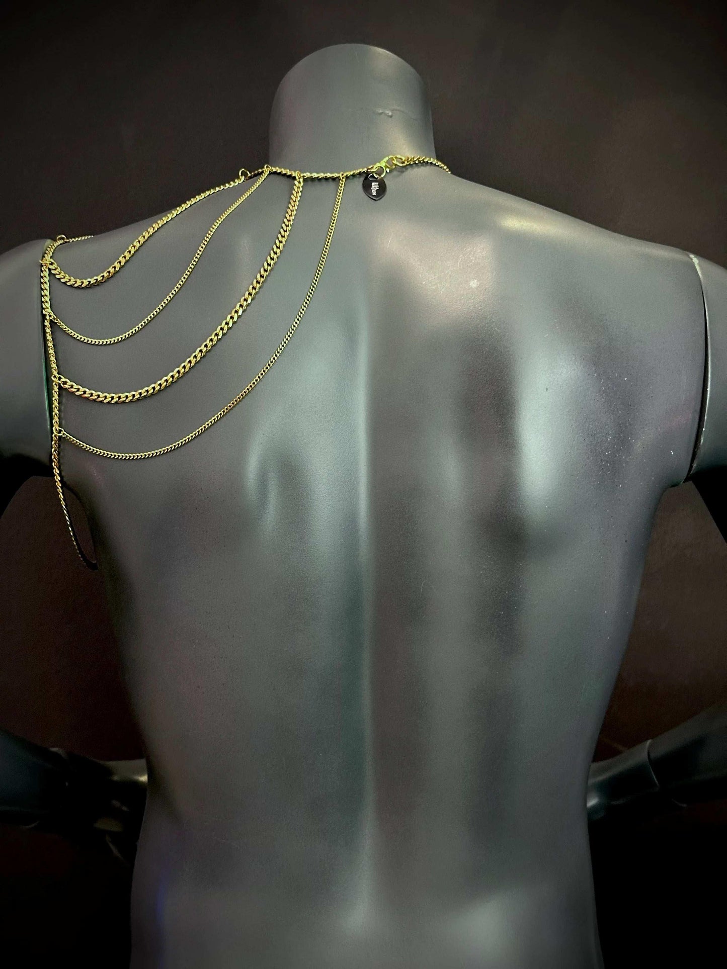 gold chain jewelry draped on matte gray mannequin back, elegant and stylish