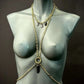Gold chain body jewelry with black pendant on gray mannequin, elegant and bold style