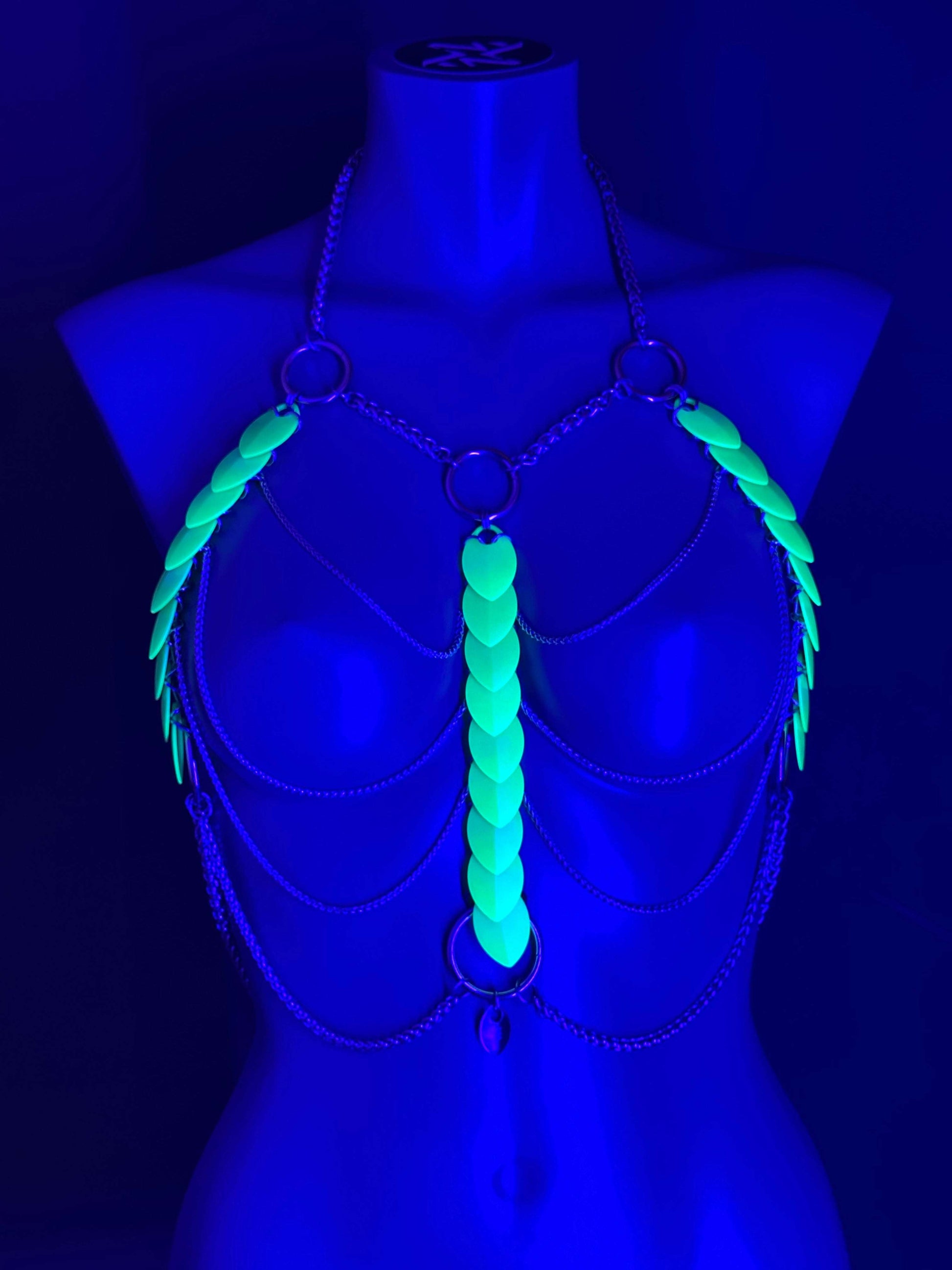 Body harness with neon green glowing scales and silver chains on blue mannequin, futuristic and edgy vibe