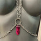 Silver chain body jewelry with pink metallic leaf pendant on gray mannequin, edgy and bold
