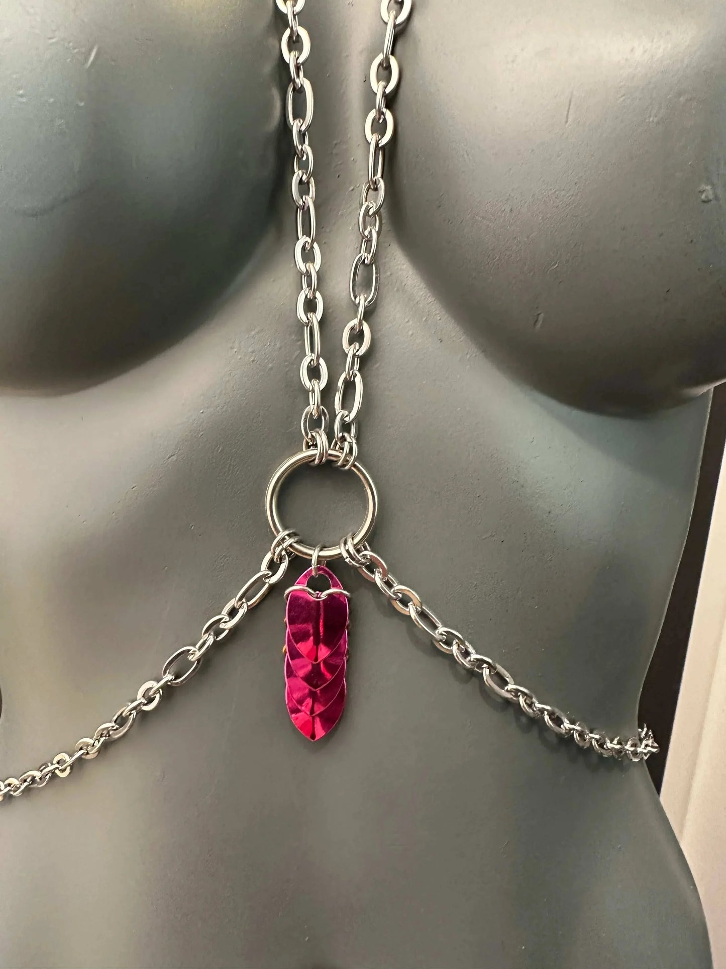 Silver chain body jewelry with pink metallic leaf pendant on gray mannequin, edgy and bold