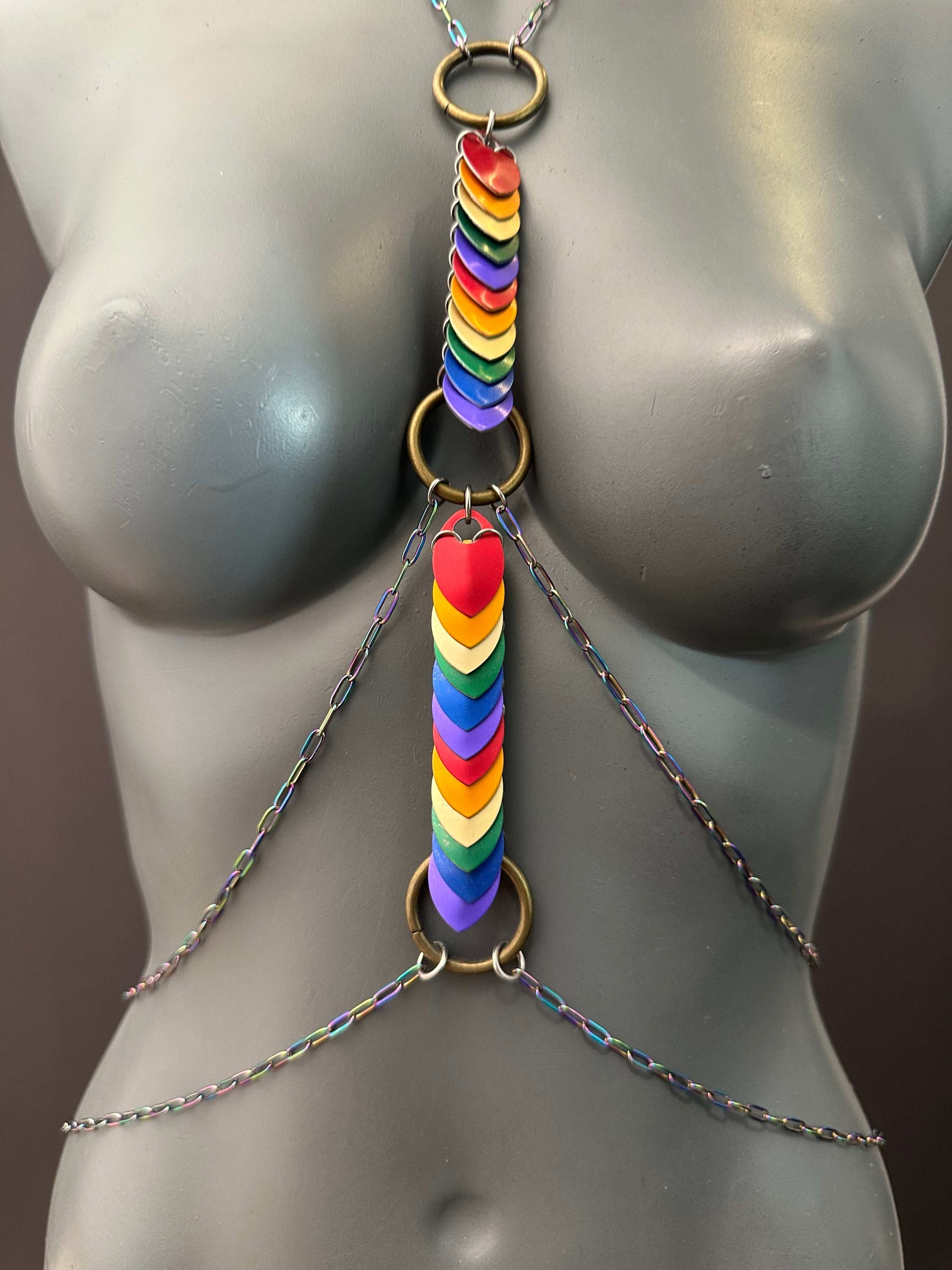 Rainbow heart body chain with multicolor links and brass rings on gray mannequin, bold and joyful