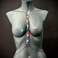 Body chain jewelry with rainbow heart charms on black mannequin, modern edgy style, bold pride statement