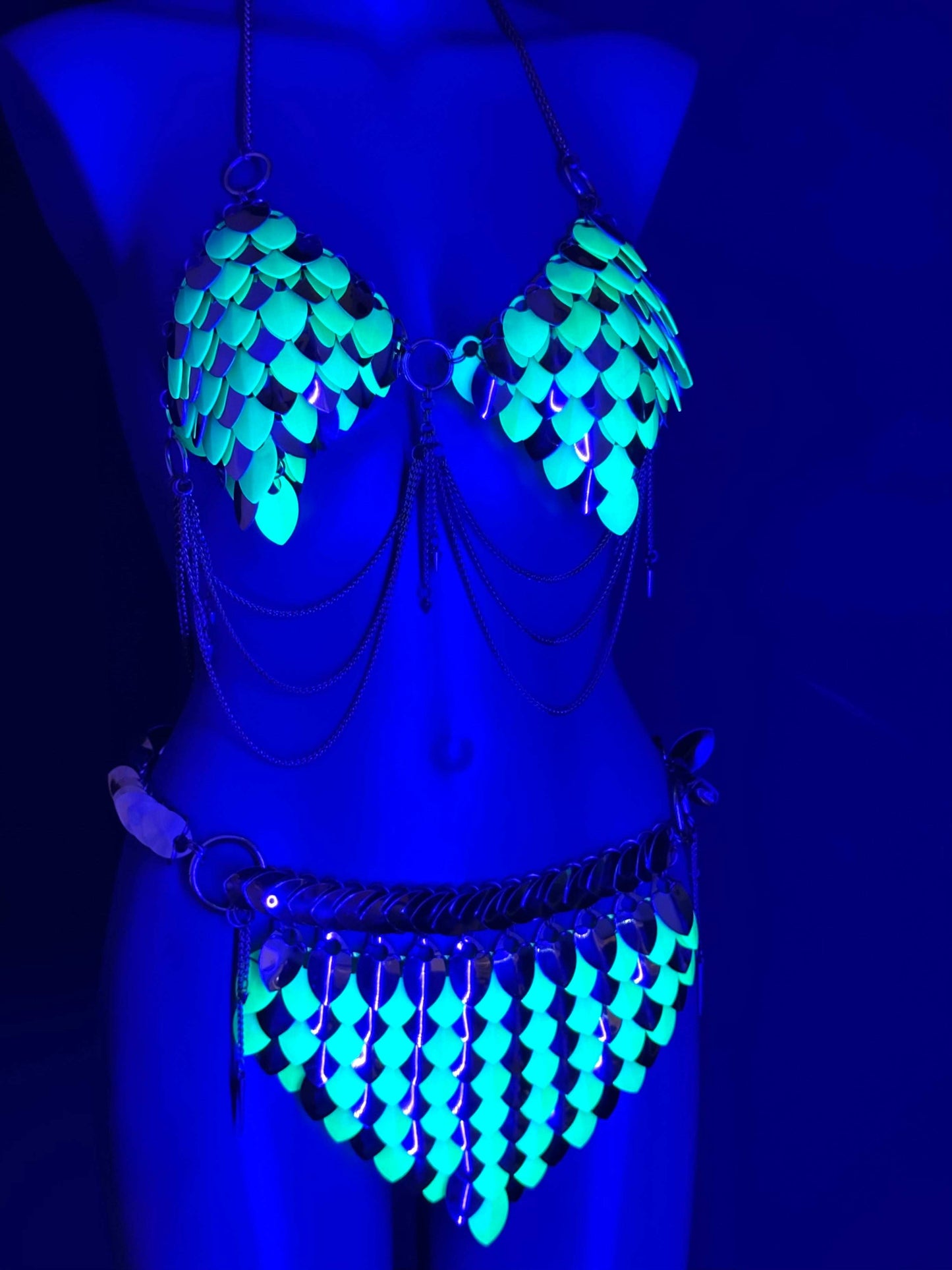 Metal bikini with glowing turquoise scales and silver chains, futuristic and bold style