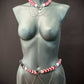 Body chain jewelry with red and white resin links and silver chains on a gray mannequin, stylish and bold