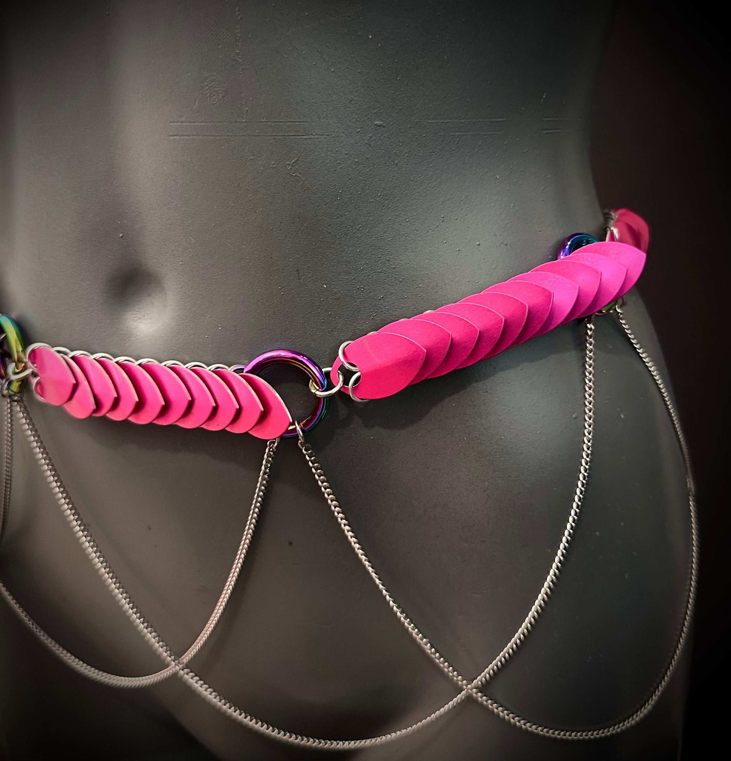 body chain with bright pink leather scales and silver chains on black mannequin, edgy and bold style