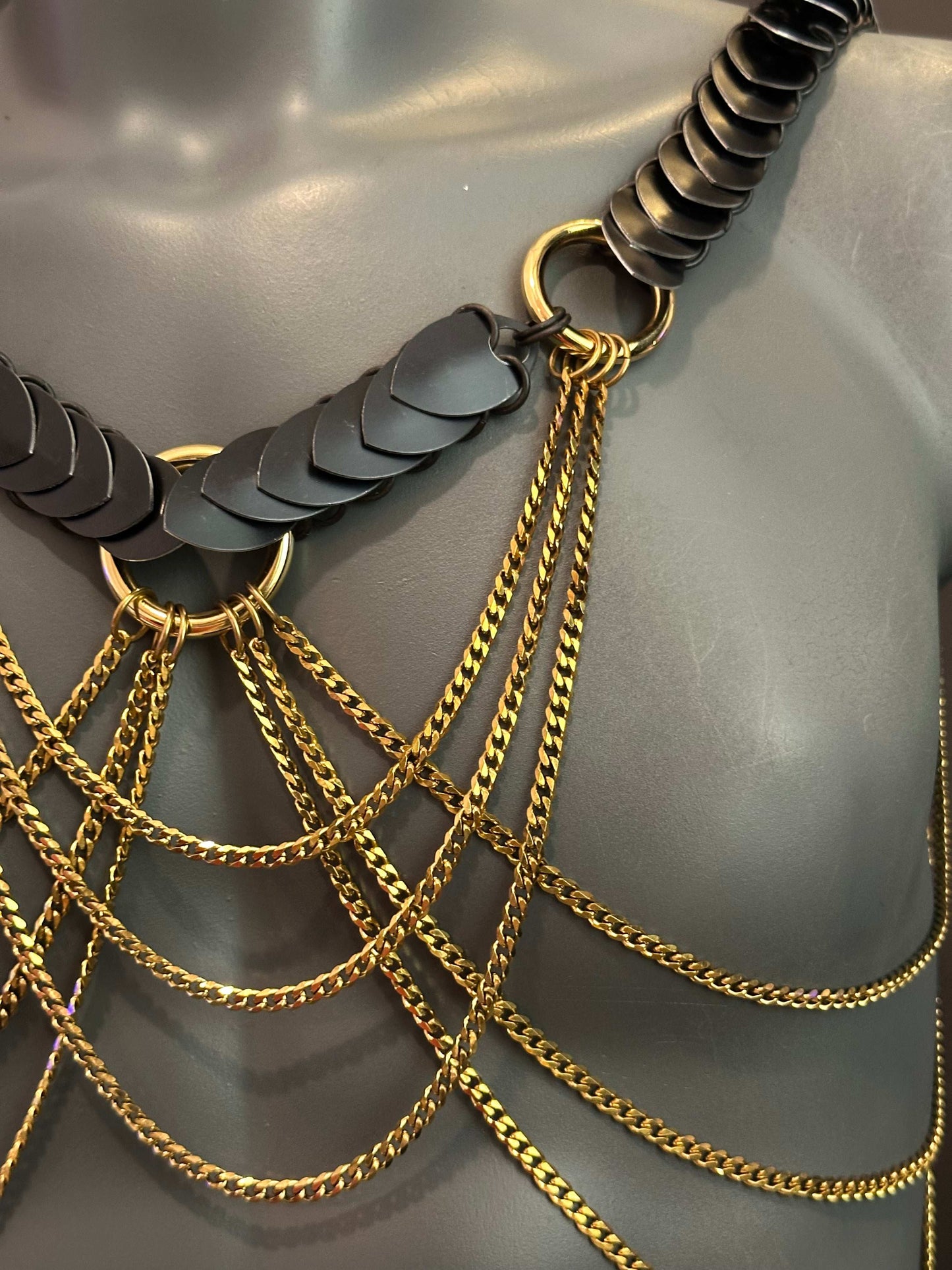 chain body jewelry with black metal scales and gold chains, stylish and bold, expressing confidence