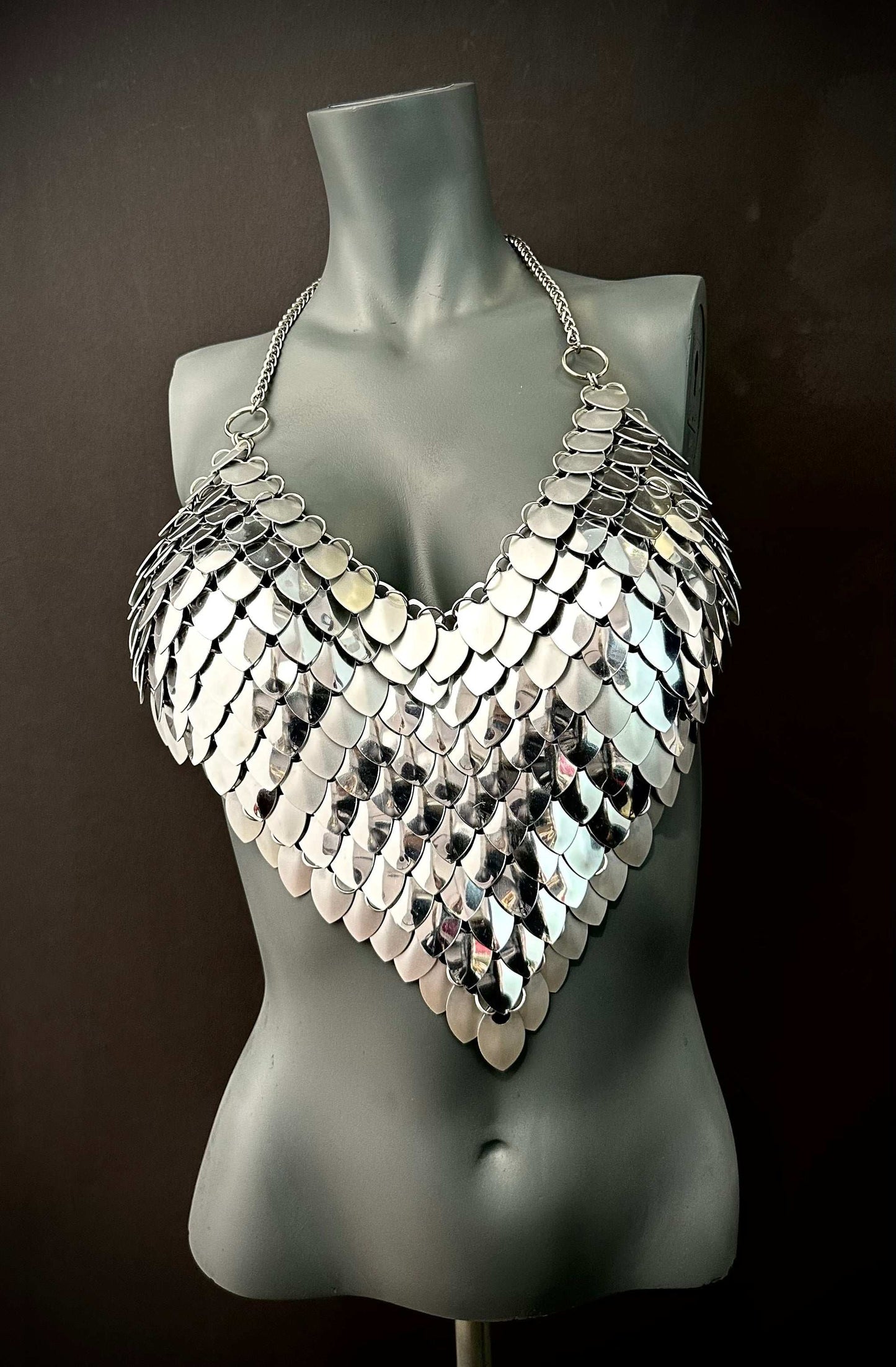Silver metal scale halter top on gray mannequin, edgy futuristic fashion, bold confident style