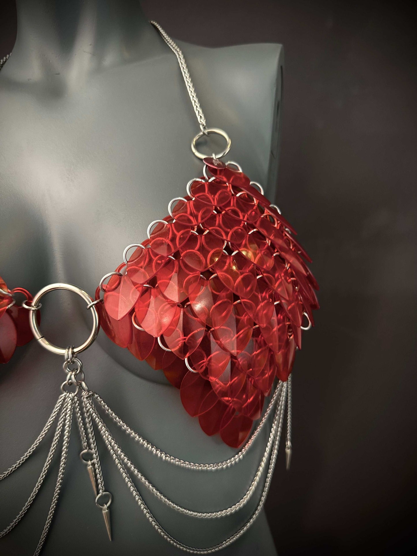 red scale bra with silver chains and spikes on grey mannequin, edgy wearable art, bold style