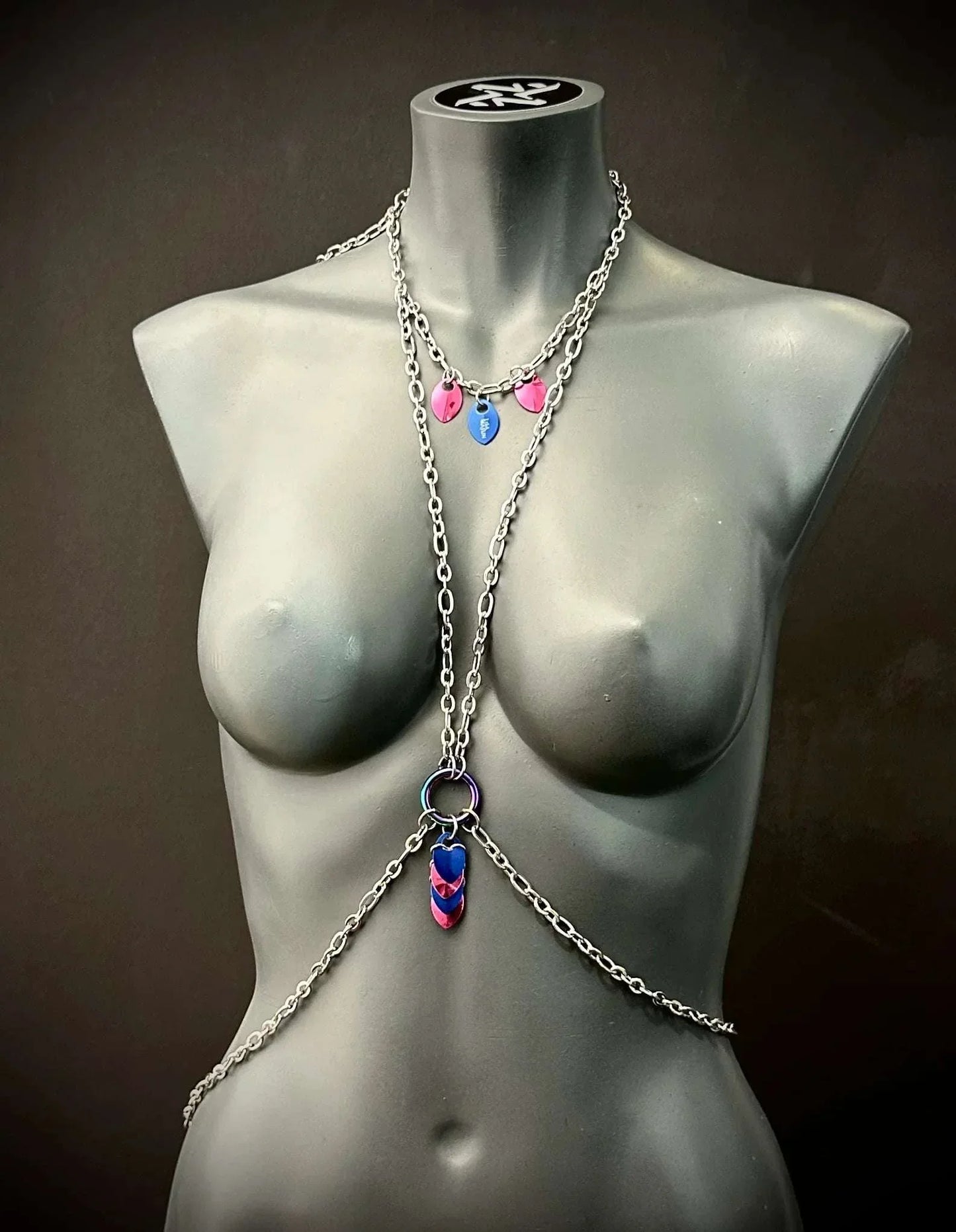 Silver body chain with pink and blue heart charms on gray mannequin, stylish and bold