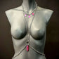 body chain jewelry in silver with pink charms on gray mannequin, bold and edgy style