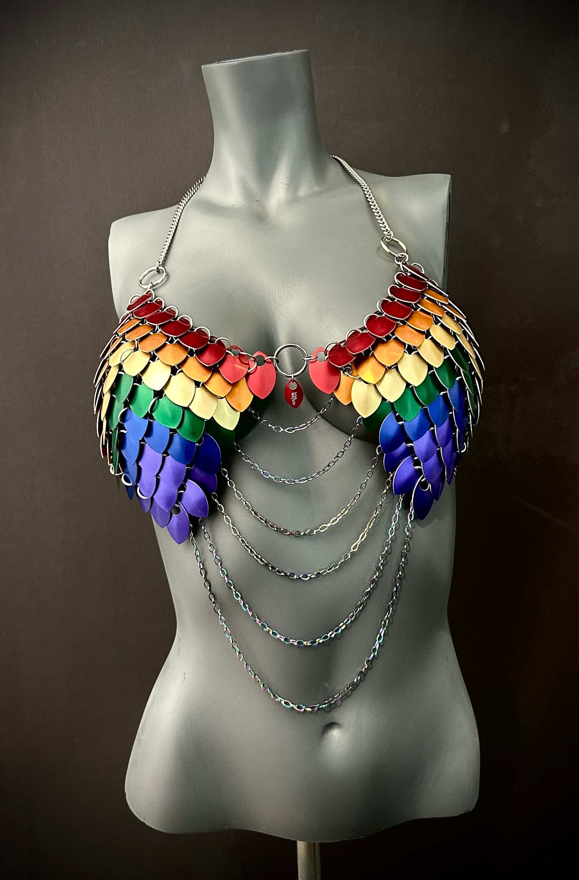 Rainbow scale metal bra with silver chains on gray mannequin, bold and vibrant style, expressive and confident