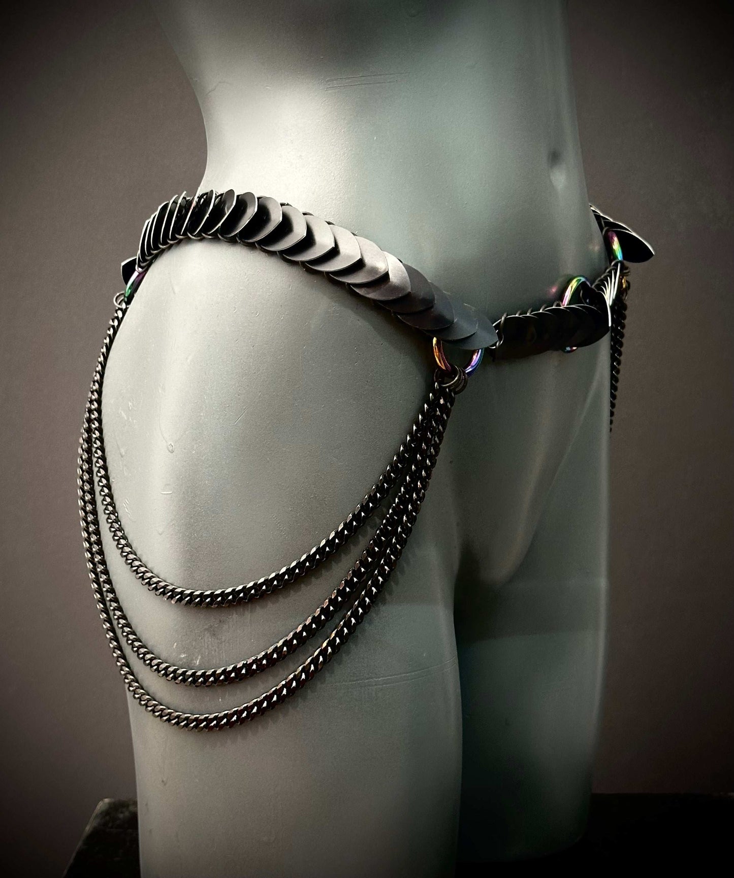 black metal chain belt with scaled details and draped chains on gray mannequin, edgy style, bold vibe
