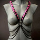 Body harness with pink and black scales and black chains on gray mannequin, edgy and bold style