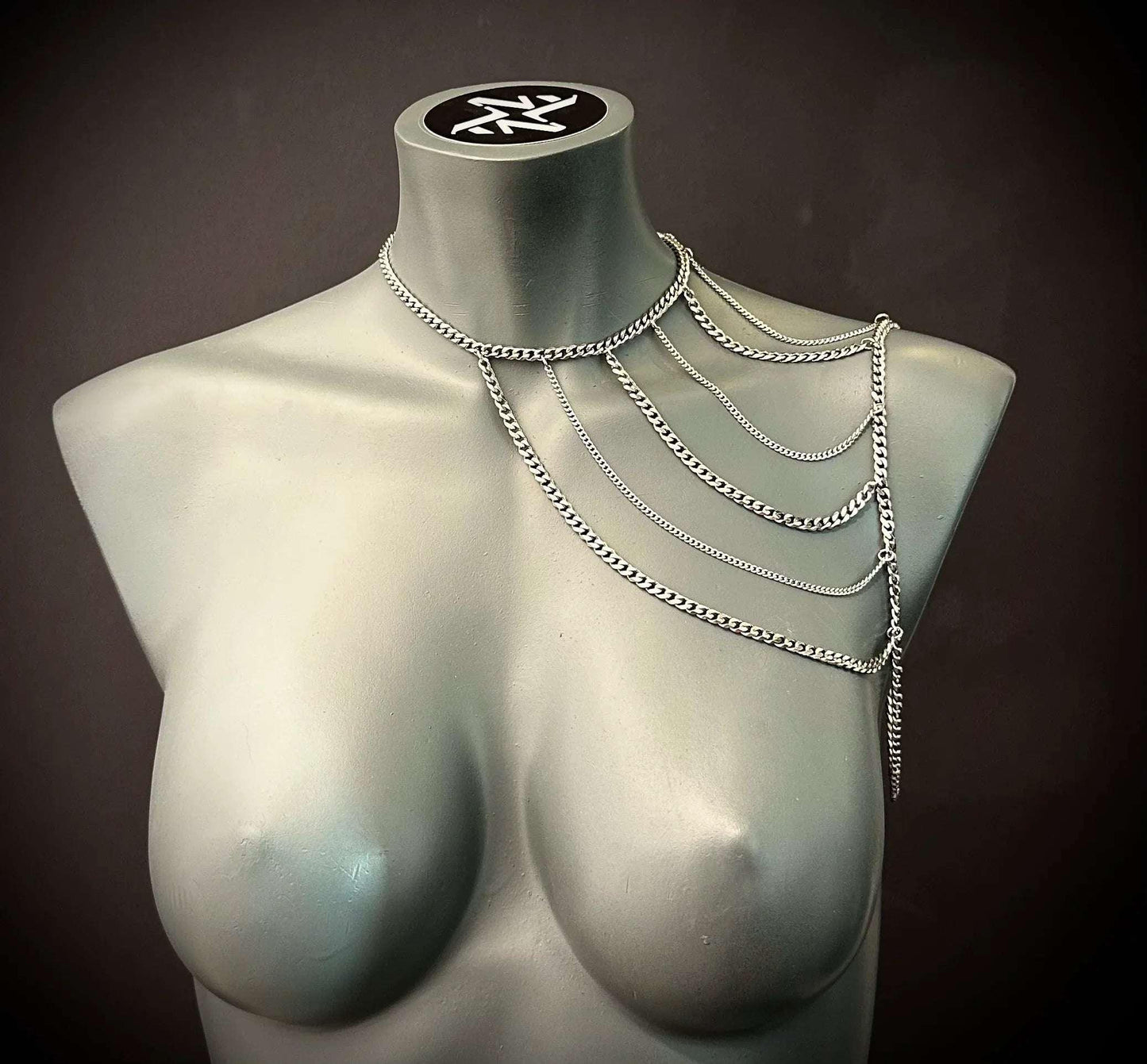 Silver chain necklace with layered design draped on gray mannequin, modern and edgy style
