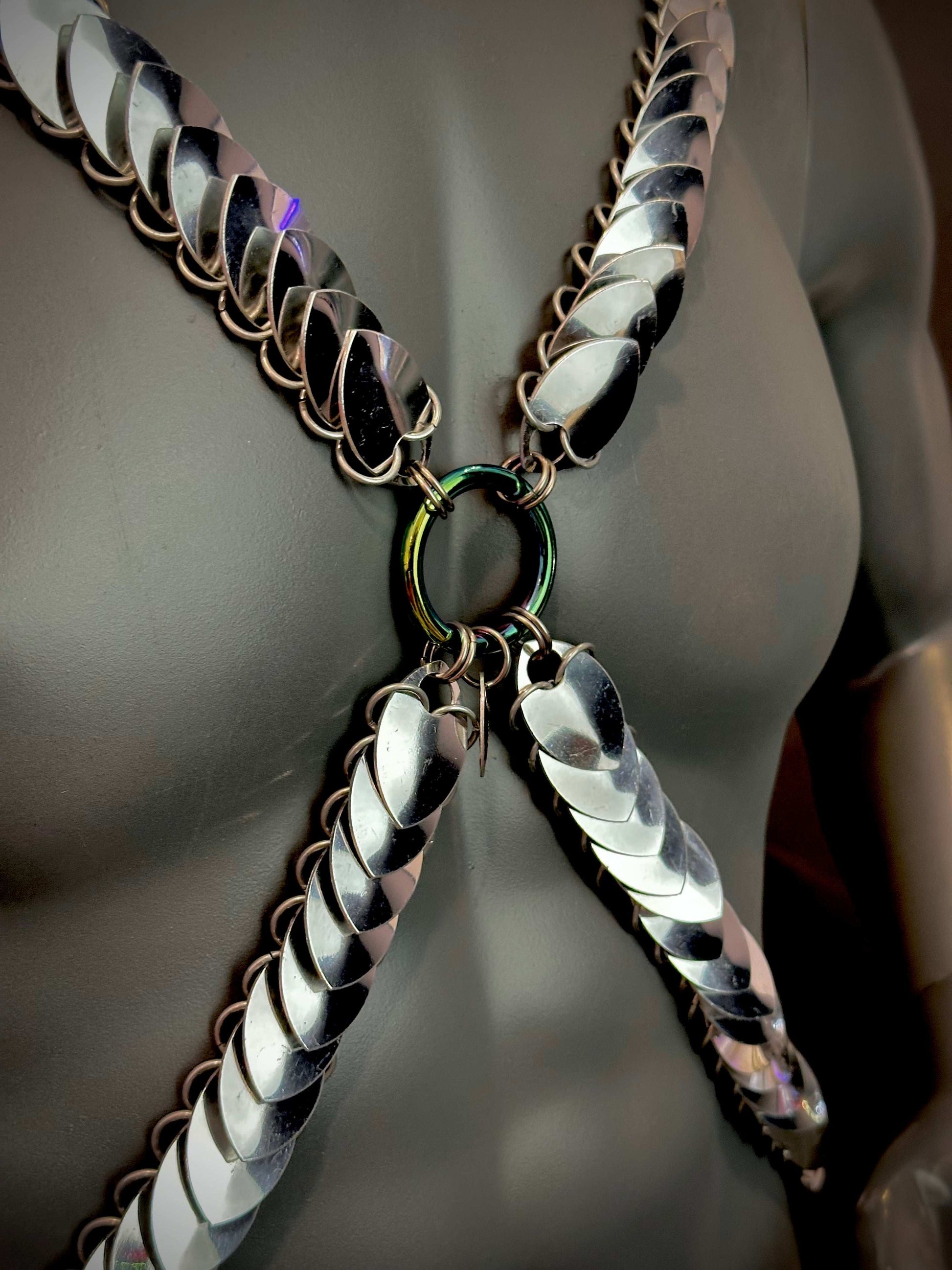 Metal chain harness with silver scales and rainbow ring on dark mannequin, bold and edgy fashion