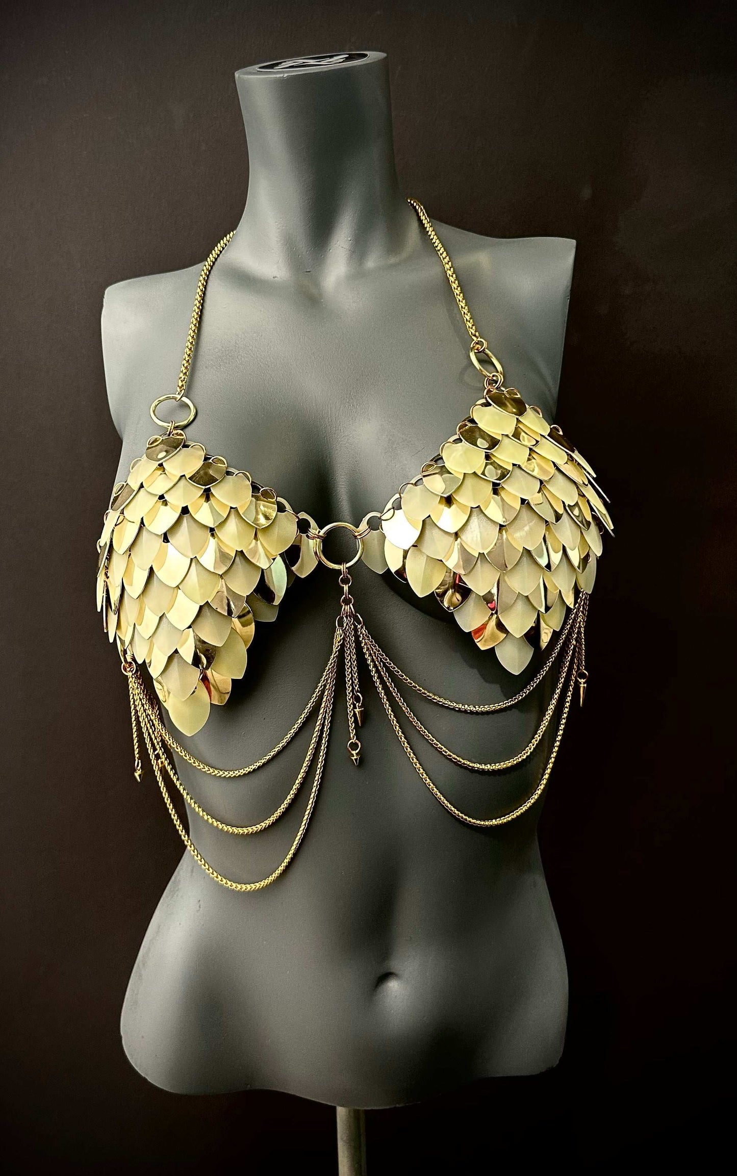 Gold metal scale bra with chain details on black mannequin, bold and glamorous fashion