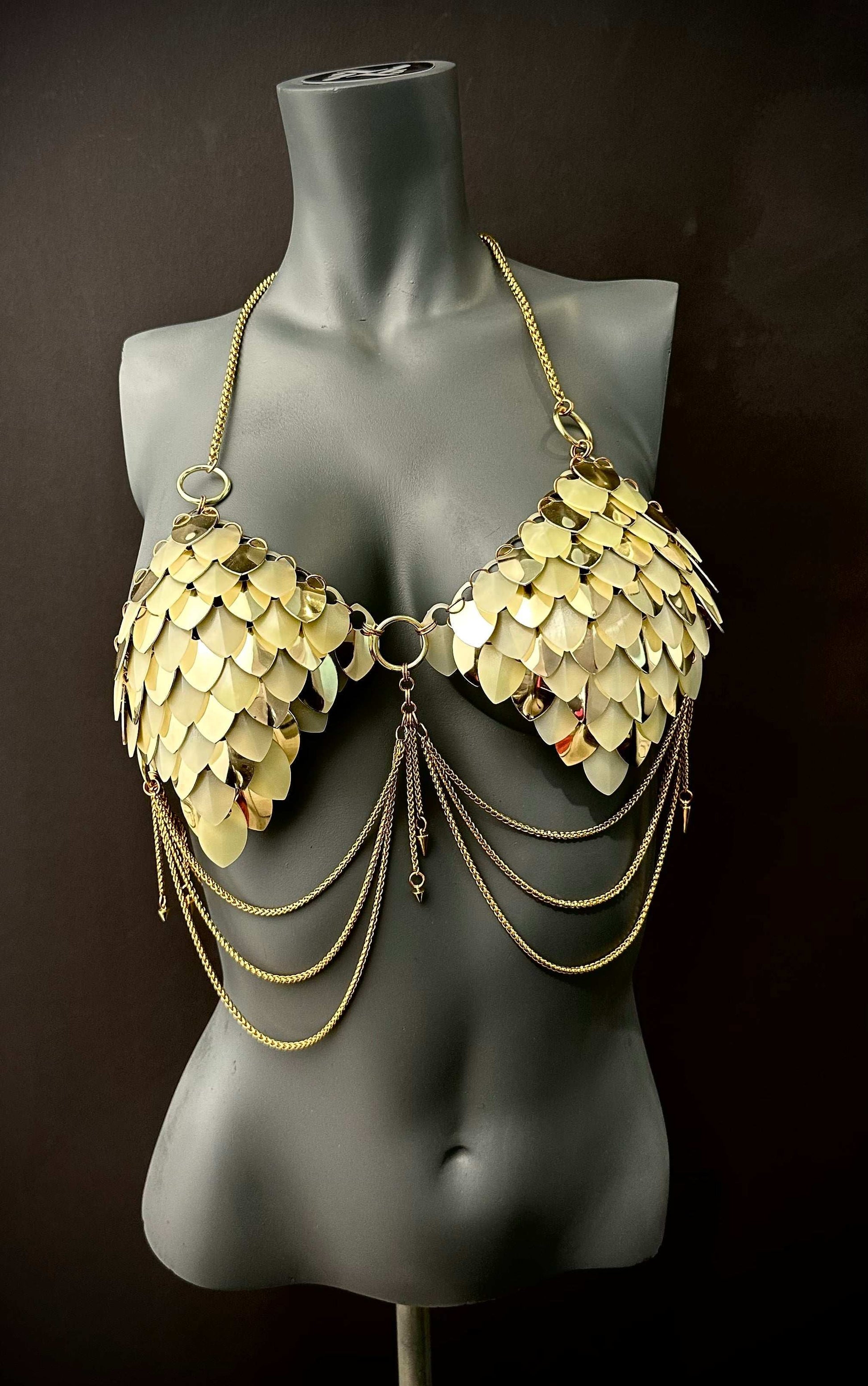 Gold metal scale bra with chain details on black mannequin, bold and glamorous fashion