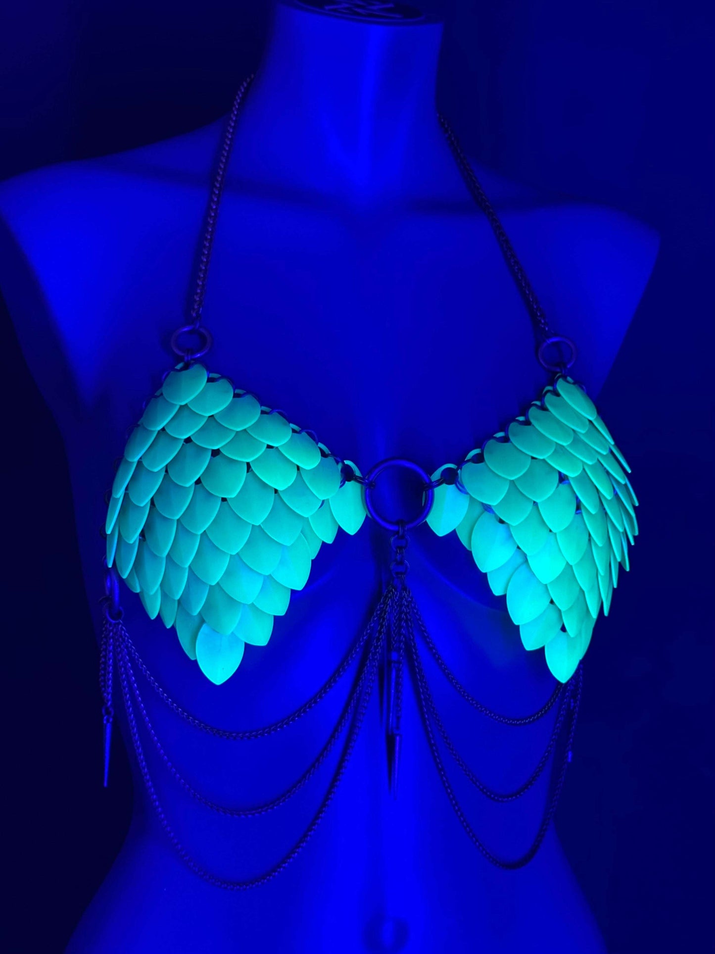 Chain bra with turquoise scales and metal chains, glowing under blue light, evoking edgy allure