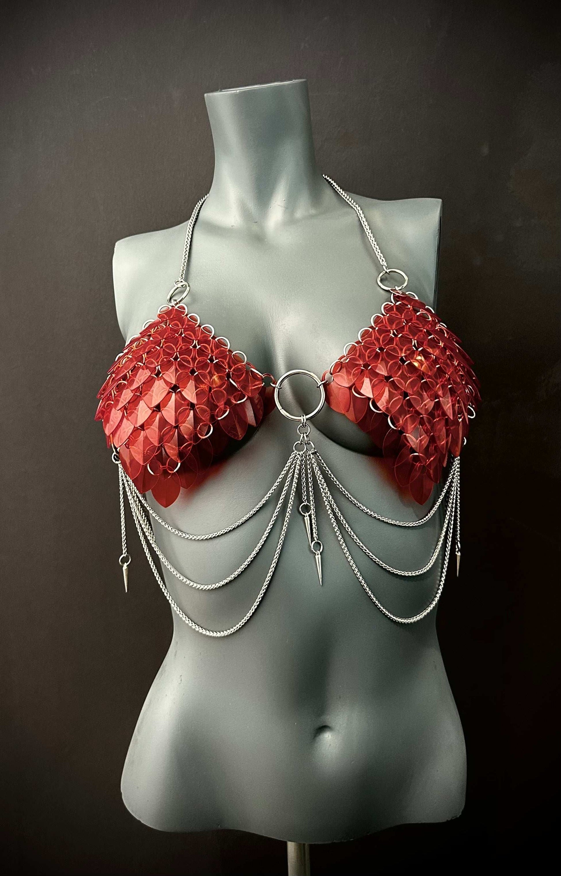 Red scale chainmail bikini top with silver chains on grey mannequin, edgy and bold fashion