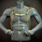 Gold chain body harness on gray mannequin, stylish edgy accessory, bold confident fashion