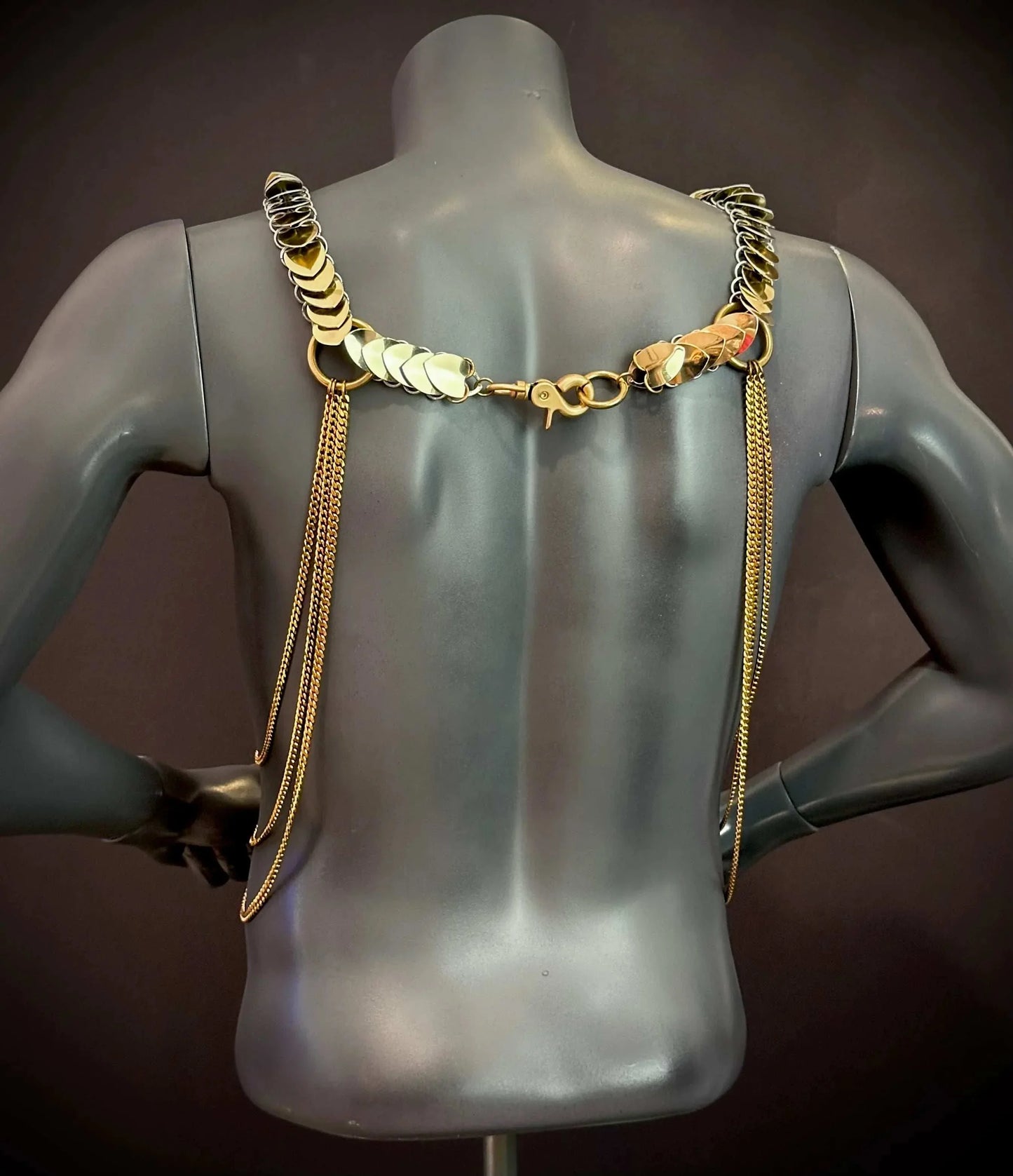 gold chain harness with shiny plates on black mannequin back, edgy and bold style, confident vibe
