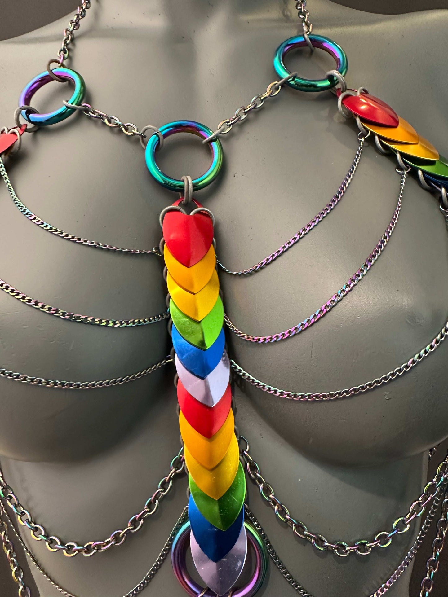 rainbow-colored chain harness with layered heart links and iridescent metal rings, bold and expressive
