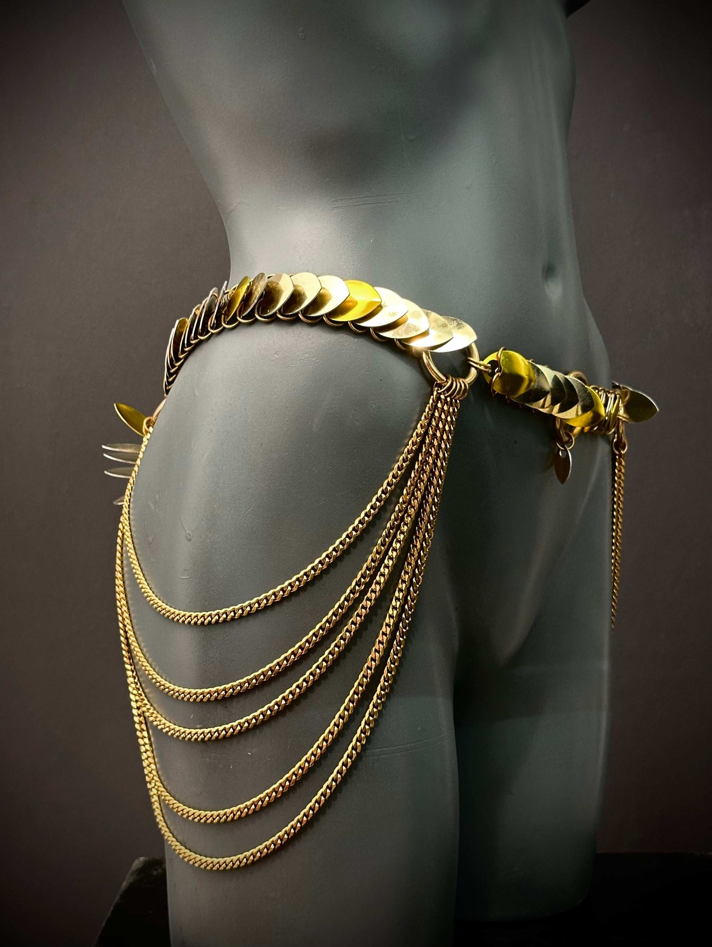 Gold chain belt with layered links and chains on gray mannequin, elegant and bold fashion