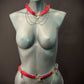 Body chain jewelry in red and gold with black spikes, edgy and bold style on matte gray mannequin