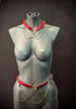 Body chain jewelry in red and gold with black spikes, edgy and bold style on matte gray mannequin