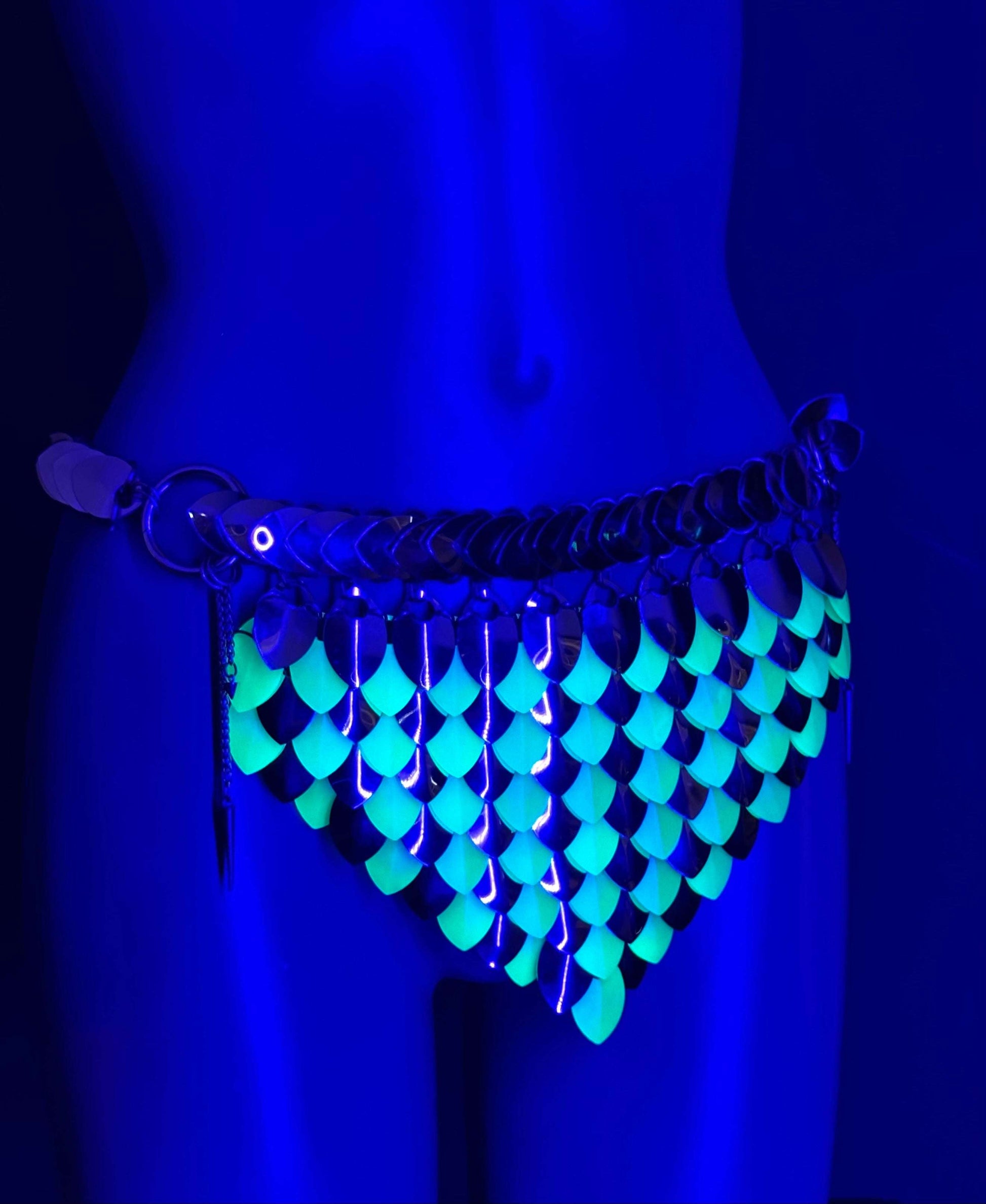 glowing green scale chainmail belt on mannequin hip under blue light, futuristic edgy style