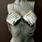 Silver metal scale bra with chain drapes on gray mannequin, edgy style, bold confidence