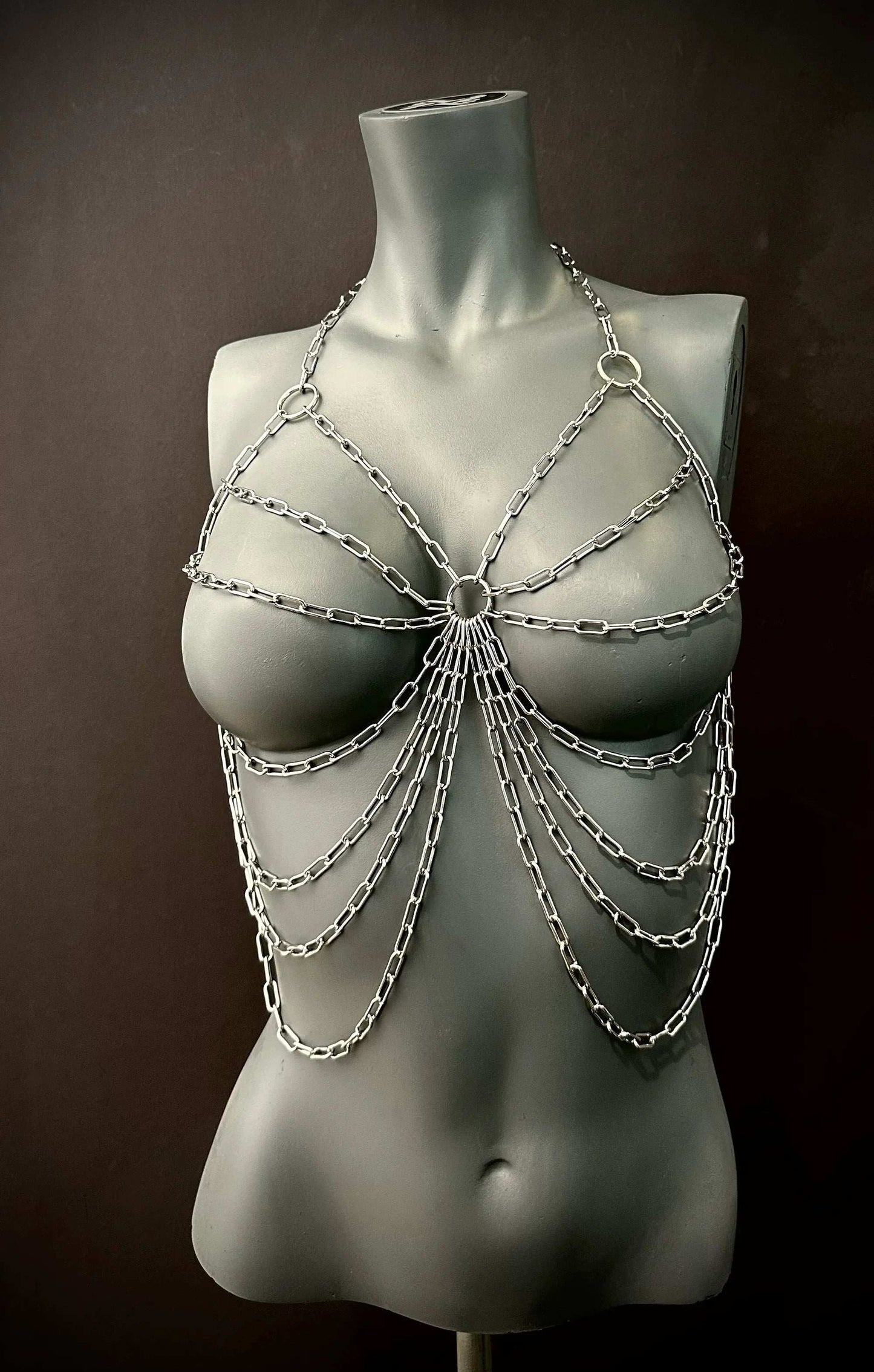 Silver metal chain body harness on gray mannequin, edgy style, bold and confident vibe