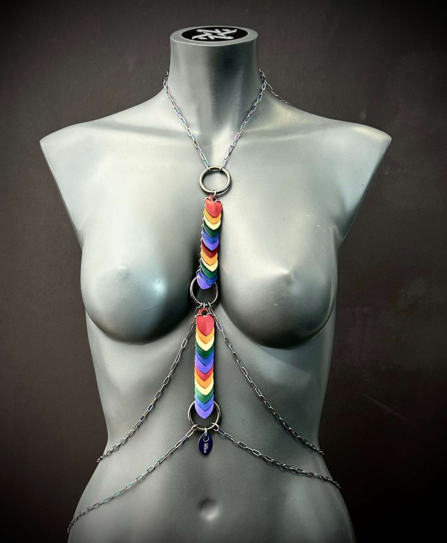 Rainbow heart chain body harness on gray mannequin, colorful and vibrant style, bold and expressive