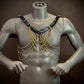black leather harness with gold chains on gray mannequin, edgy style, bold confidence