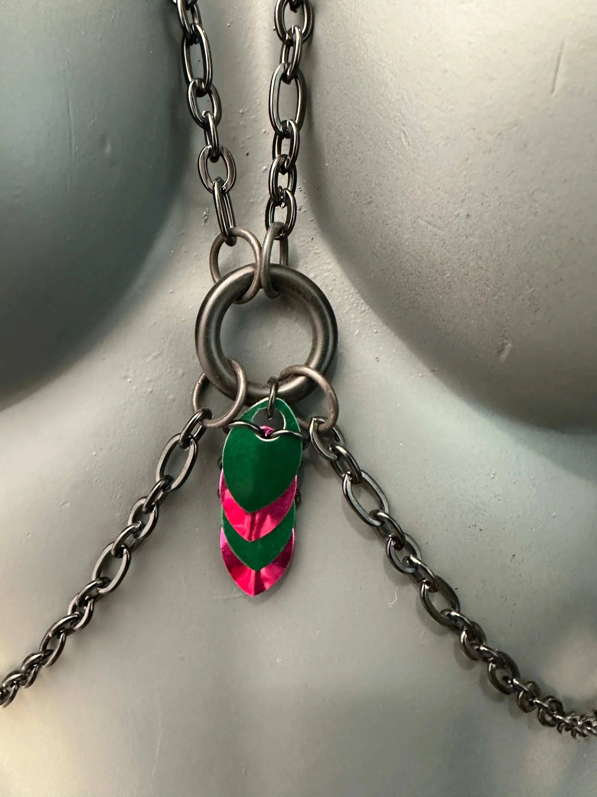 Chain necklace with silver metal links and green-pink heart-shaped charms, edgy and vibrant
