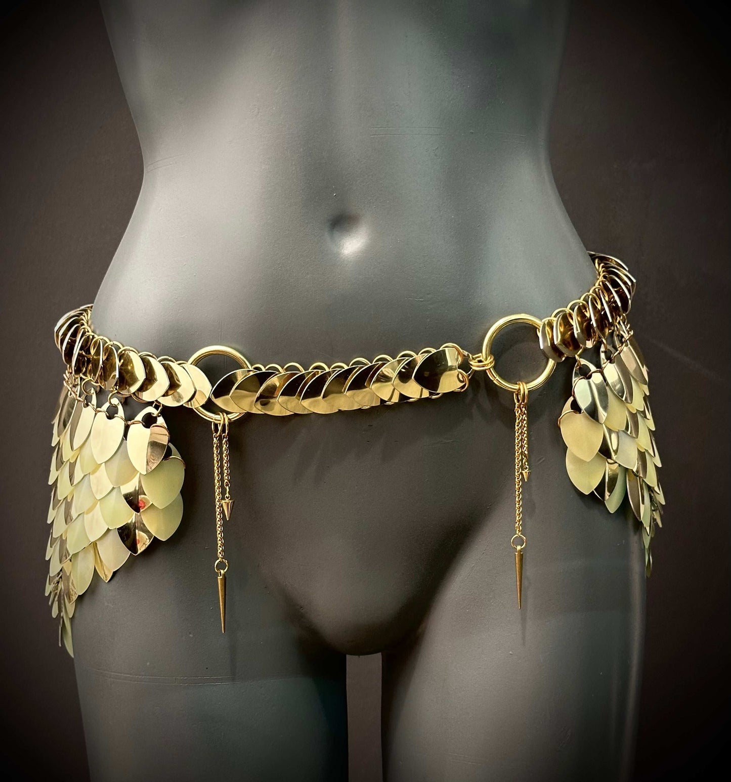 Gold metal chain belt with overlapping scales and dangling spikes, shiny and elegant style