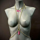 Body chain jewelry in gold with pink pendants on black mannequin, elegant and bold style