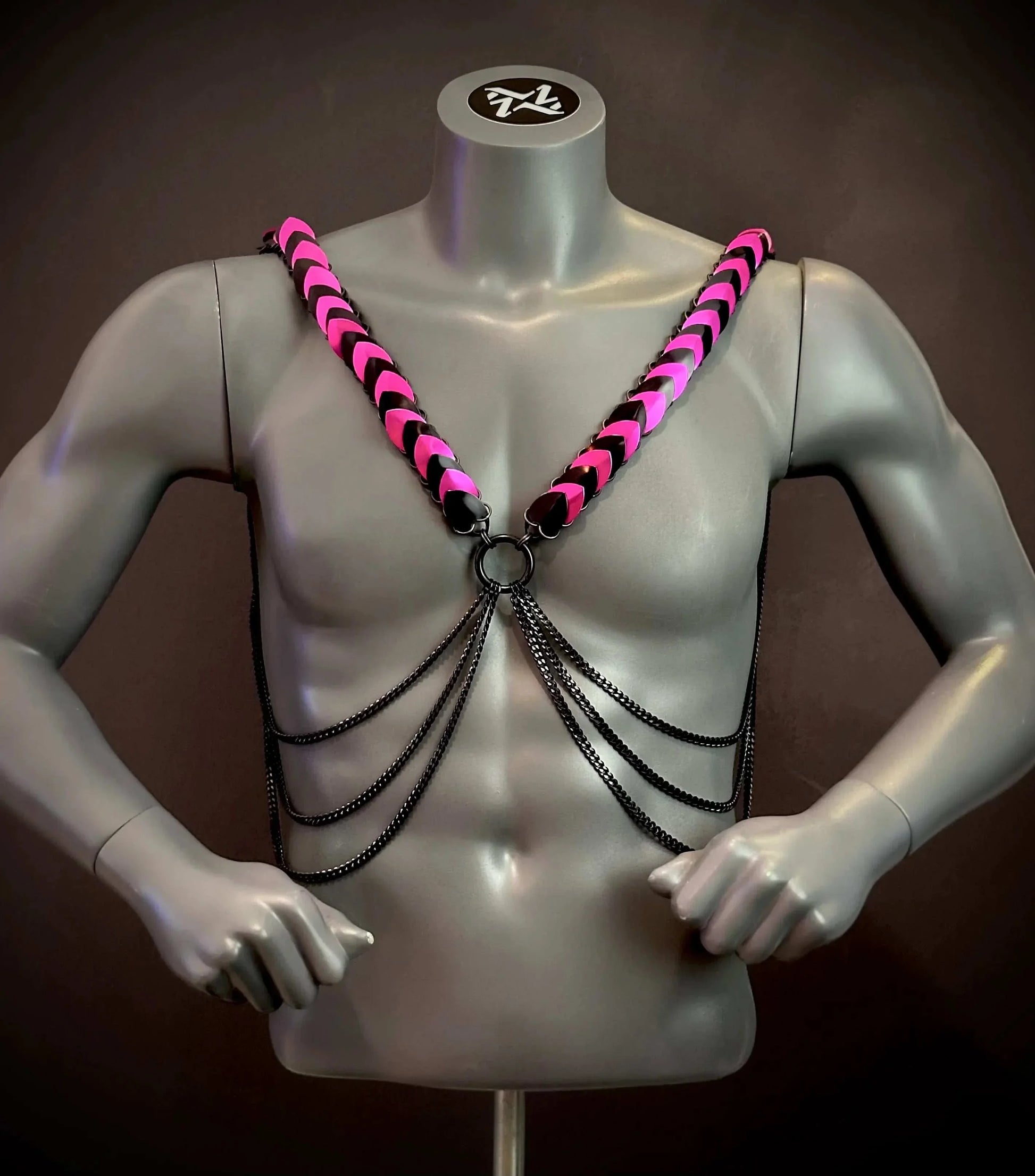 Pink and black leather harness with silver chains on gray mannequin, edgy and bold style