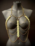 Golden body chain jewelry with green leaf accents on black mannequin, elegant and bold