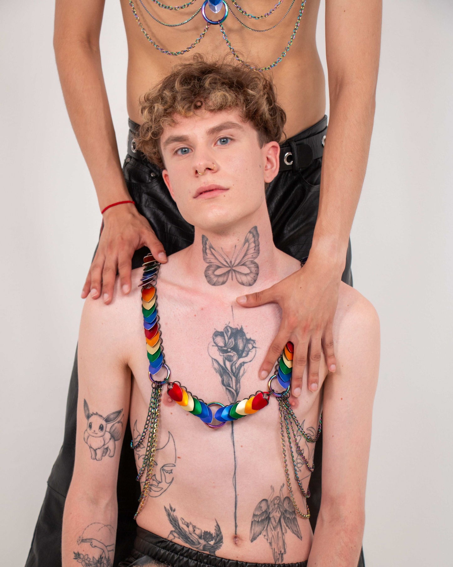 Rainbow heart harness with chains on tattooed shirtless man, modern colorful style, confident vibe