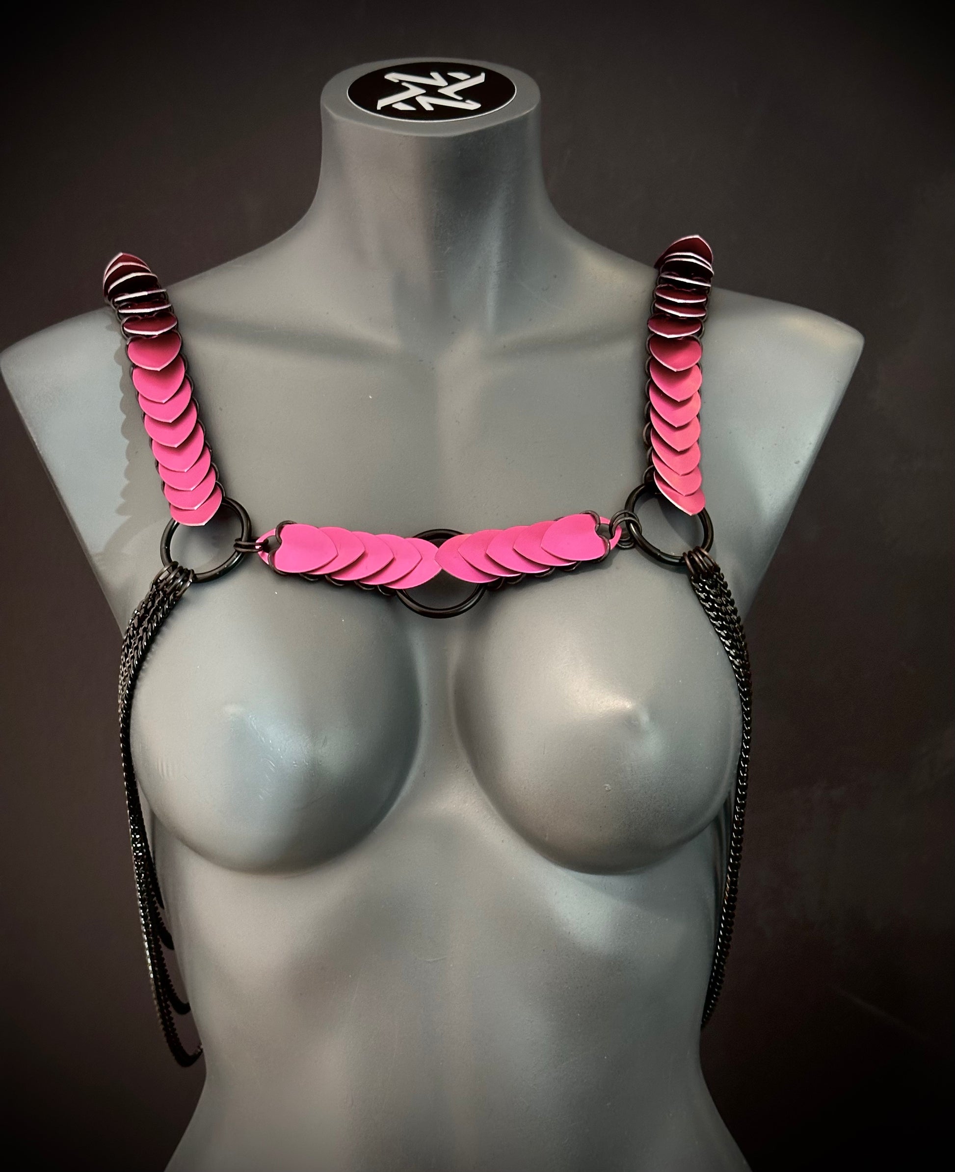 pink chain harness with black metal rings and chains on gray mannequin, edgy and bold style